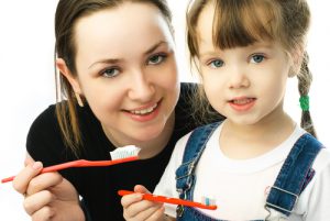 mother teaching her daughter brushing teeth